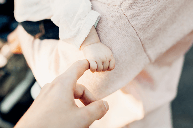 Baby holding adult finger