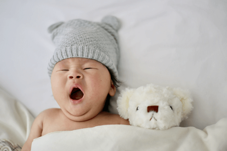 Yawning baby with teddy bear